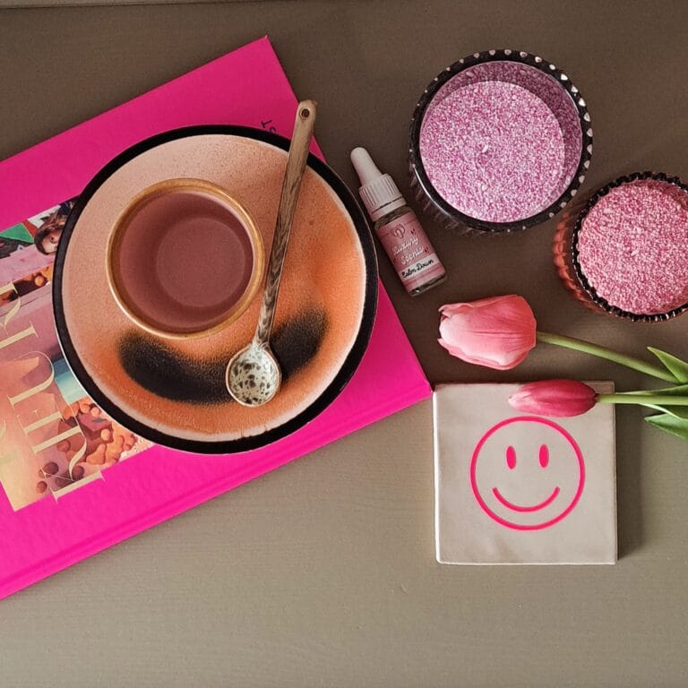 Flatlay met kopje thee, roze kaarsenzand, geurolie en tulpen op een stijlvolle ondergrond, creëert een gezellige en trendy lifestyle setting met Pearl Candles.